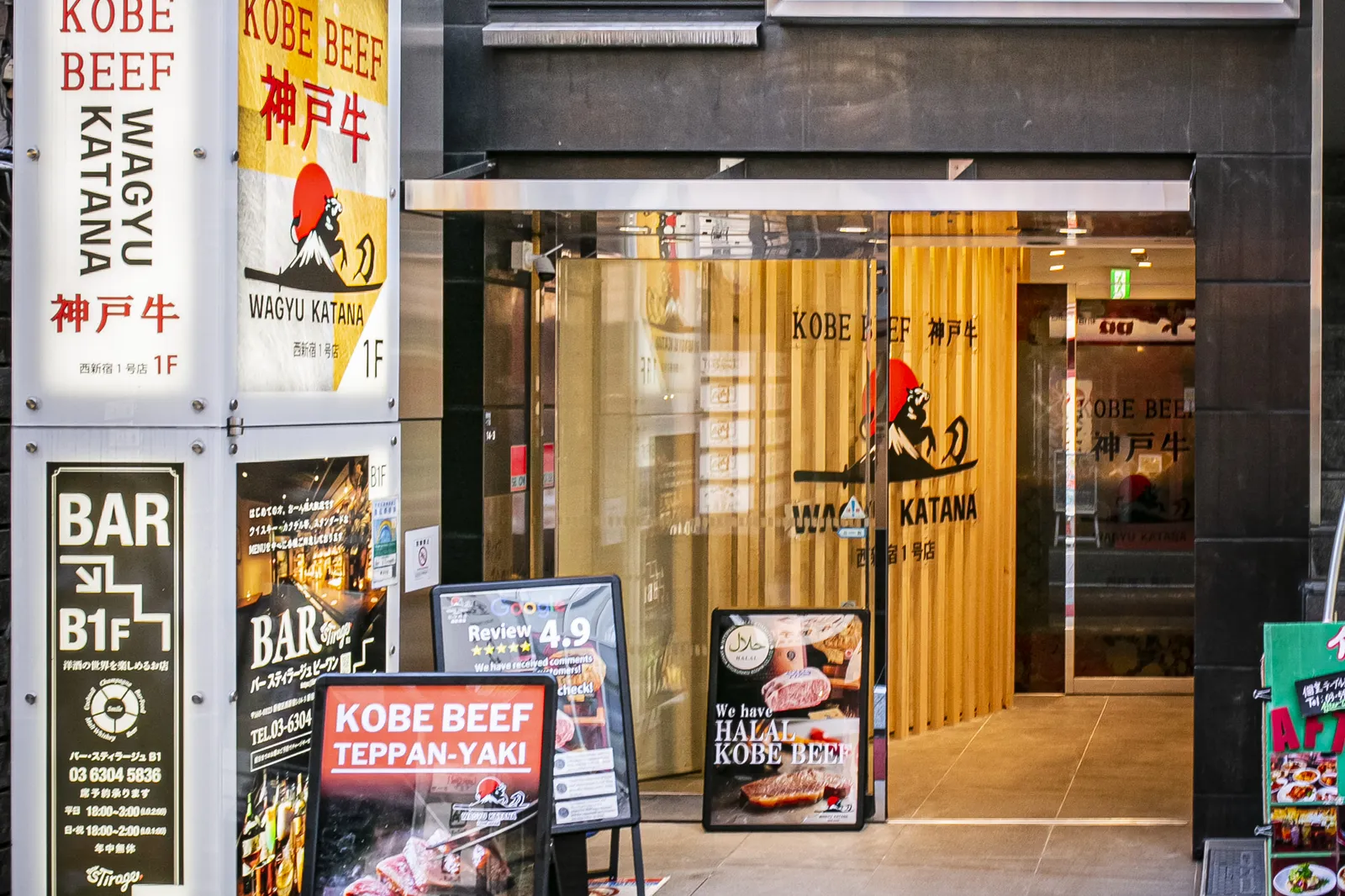 Ground-floor entrance, with Kobe beef teppanyaki signboards along a yellow lattice wall