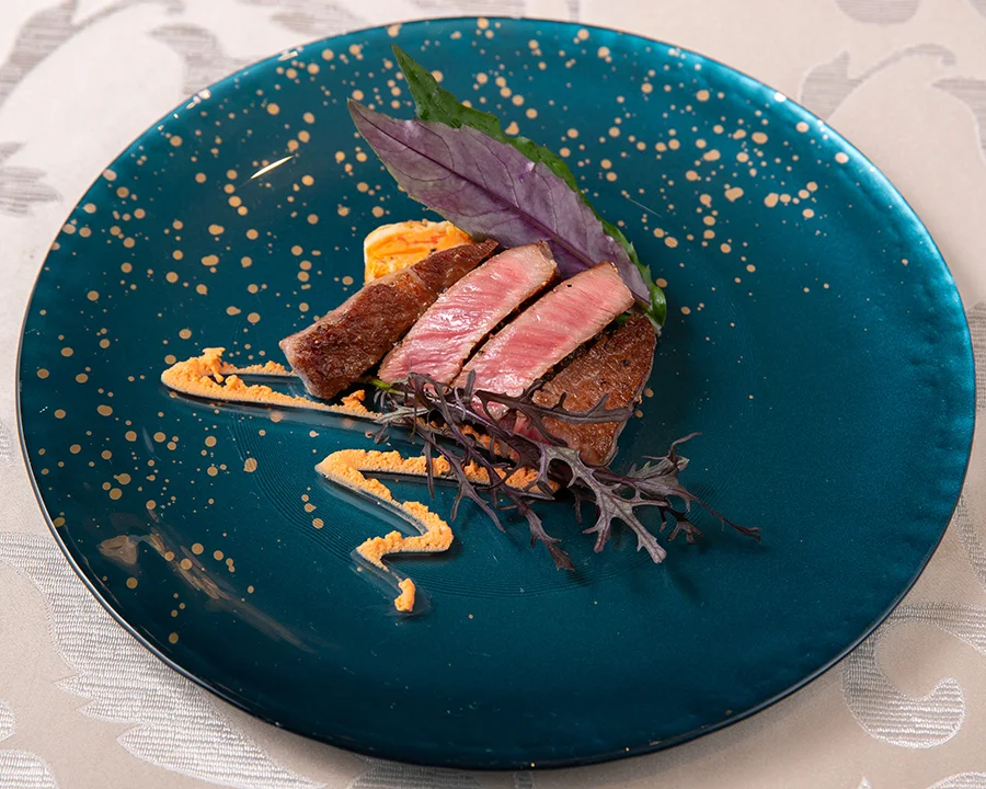 Kobe beef steak plated with sauce on a deep-blue dish