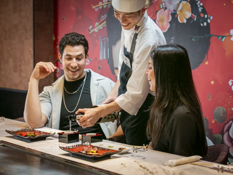 A member of staff explaining a dish to guests at the counter